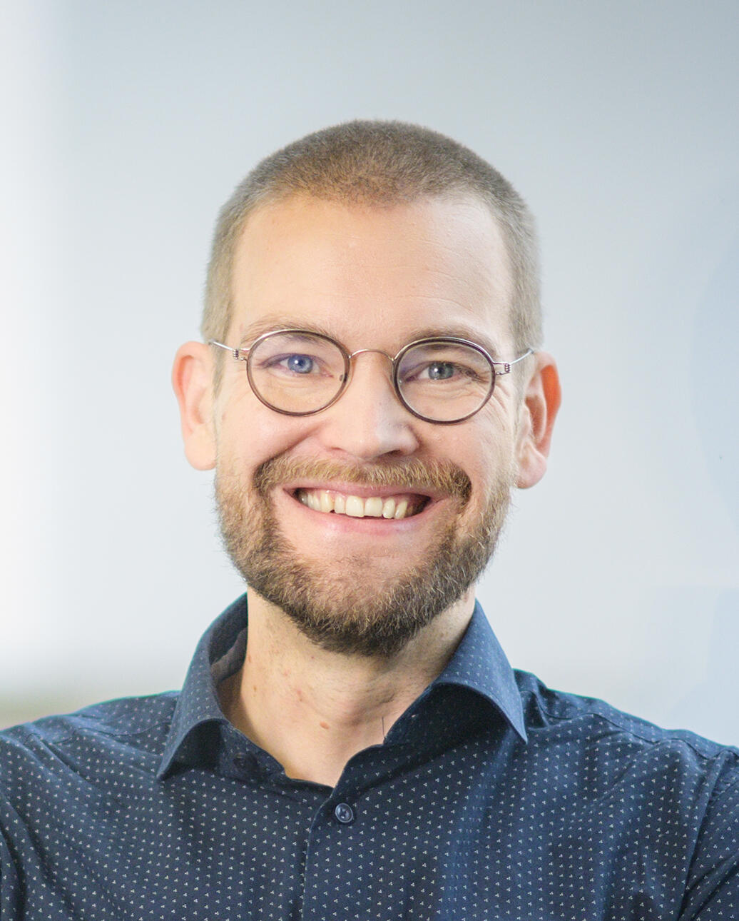 Eetu Niemi—enterprise architecture consultant, author, and speaker Smiling man with glasses, a beard, and short hair. He is wearing a dark blue button-up shirt, with a light-colored wall in the background.